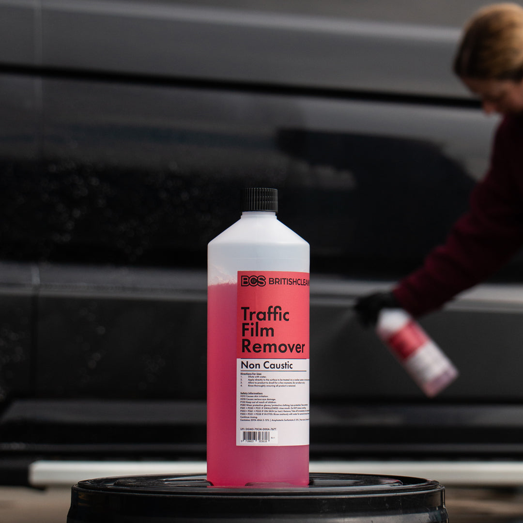 BCS Traffic Film Remover bottle with a person using a spray bottle in the background.