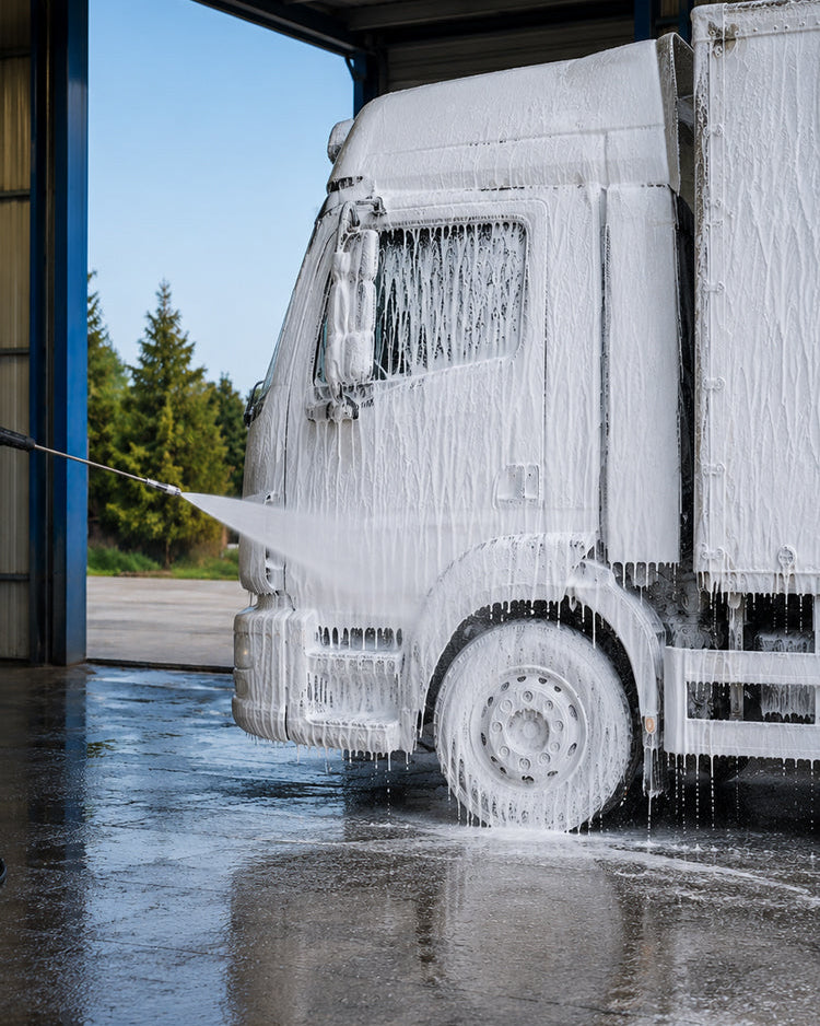 Lorry covered in snow foam being rinsed