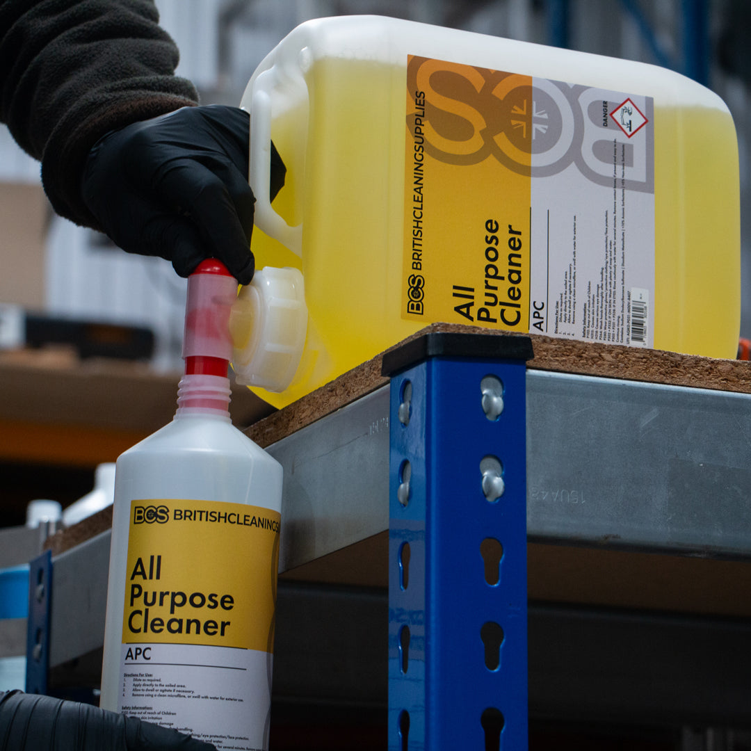 Person pouring BCS All Purpose Cleaner from a large container into a smaller bottle.